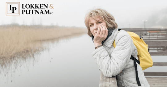 middle age woman wearing a jacket and yellow backpack looking out over water